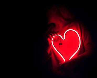 a heart shaped neon sign in the dark
