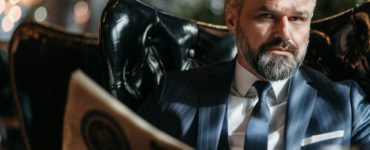 Stylish businessman with a beard reading a newspaper indoors.