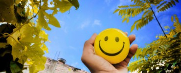 a hand holding a yellow smiley face ball