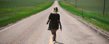 a woman walking down the middle of a road