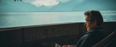 man sitting while holding a book watching on body of water