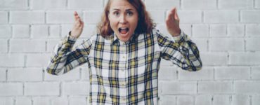 Woman with hands raised shouting in frustration.